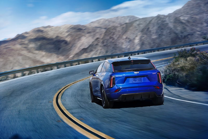 Rear View of a Blue 2026 OPTIQ-V Driving on a Curve of a Mountain Row | Ed Martin Cadillac in ANDERSON IN