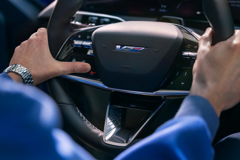 Close-up of a Man About to Press the V-Button on the 2026 OPTIQ-V Steering Wheel | Ed Martin Cadillac in ANDERSON IN